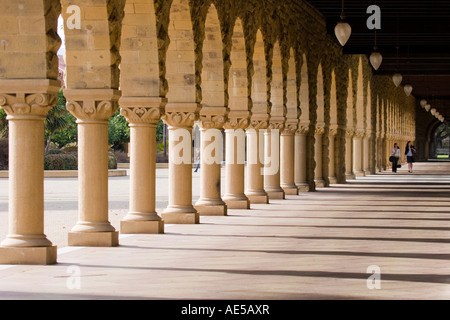Portikus in Stanford Universität Main Quad mit Schattenwurf von Säulen aus Sandstein Bogen und Passanten in Ferne Stockfoto