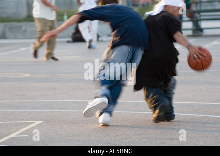 Black And White Boys in weite Kleidung spielen Basketball auf Stadtgerichte in Venice Beach Stockfoto