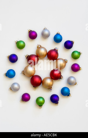 Rote und goldene Weihnachtskugeln in einem Kreis umgeben von kleinen bunten Urlaub Ornamente vor einem weißen Hintergrund Stockfoto