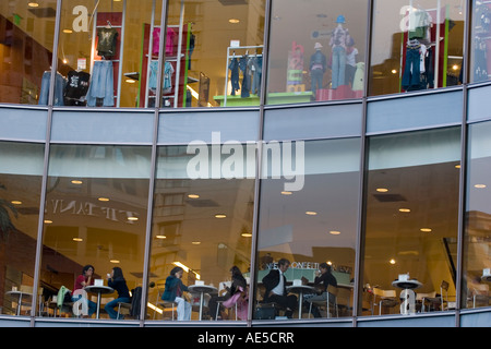 Menschen, die eine Pause vom Einkaufen in einem Kaufhaus Café von außen durch Glasfenster Bild gesehen Stockfoto