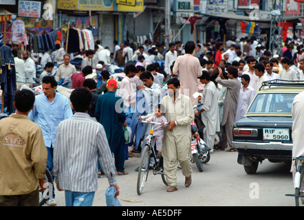 Mann, die Machenschaften von Kind auf Fahrrad in belebten Straße in Islamabad in Pakistan Stockfoto