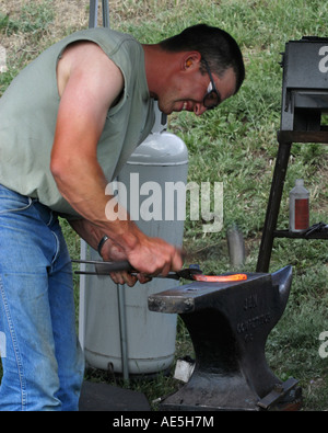 Hufschmied machen ein Hufeisen durch Stampfen rote Roheisen mit einem Hammer auf einen Amboss Stockfoto