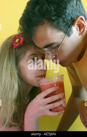 Mit zwei Strohhalmen trinken junge 20 jährige Mann und neunzehn Jahre alte Frau Paar teilen einen Erdbeeren smoothie Stockfoto
