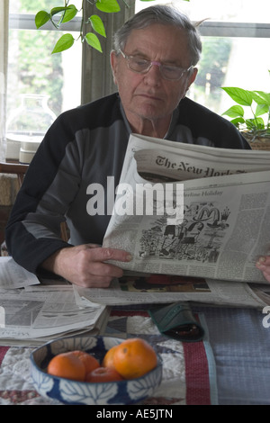 Ältere Mann in seiner Mitte der 70er Jahre die New York Times Zeitung am Frühstückstisch lesen Stockfoto