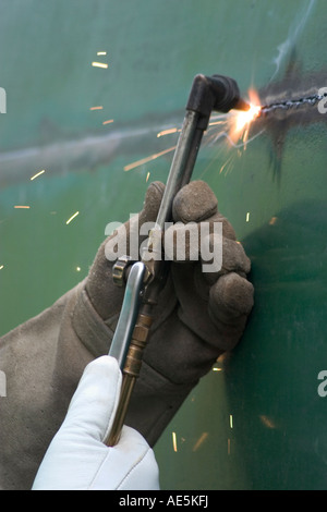Behandschuhten Händen mit Schweißer s Taschenlampe durch ein Metall-Tank schneiden Stockfoto