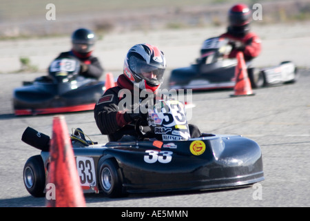 Drei gehen Kart Racer Rennen rund um eine Kurve mit orangen Kegeln auf einer Asphalt-Strecke Stockfoto