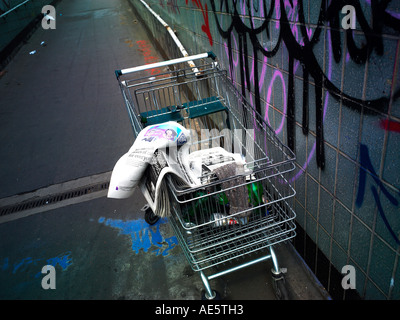 Shopping Trolley von Obdachlosen auf einem Manchester-Unterführung mit Graffiti an Wand verwendet Stockfoto