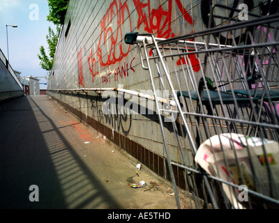 Shopping Trolley von Obdachlosen auf einem Manchester-Unterführung mit Graffiti an Wand verwendet Stockfoto