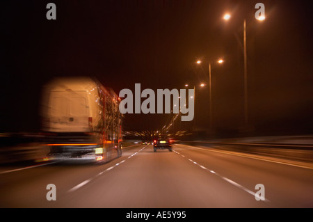 FAHRZEUG TRANSPORTER MIT GESCHWINDIGKEIT AUF DER AUTOBAHN BEI NACHT Stockfoto