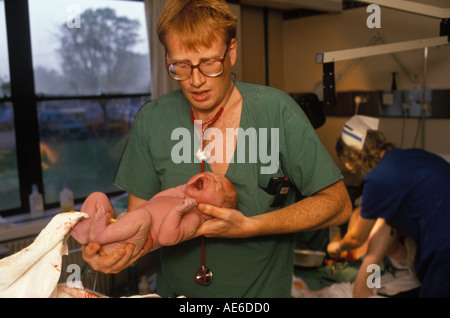 Der neugeborene NHS-Arzt Phil Hammond trägt ein schreiendes Baby, das gewogen wird. 1980er Jahre Royal United Hospital Bath Hospital Somerset 1988 HOMER SYKES Stockfoto