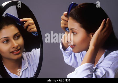 RHS70991 South Asian indischen Mädchen Kämmen ihr Haar mit Kamm vor einem Spiegel Modell Release Nummer 442 Stockfoto