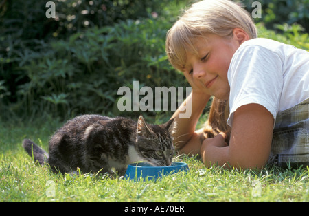 Mädchen auf der Suche auf ein Kätzchen, die Milch zu trinken Stockfoto