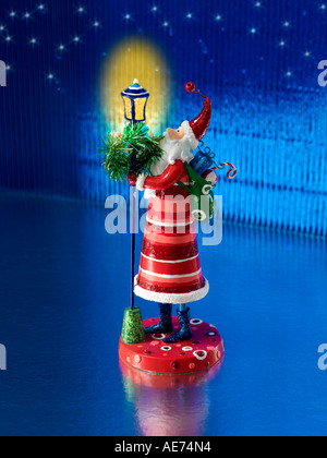 Weihnachtsmann einen Spielzeug-Sack auf seinem zurück stehen unter einem glühenden festliche Lampe oder Laterne Stockfoto