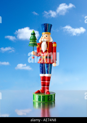 Eine rote und blaue bunt bemalte Weihnachten festlich Spielzeugsoldat auf einer blauen Himmel Landschaft mit Reflexionen Stockfoto