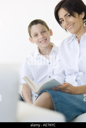 Junge und Reife Frau mit Buch, lächelnd in die Kamera Stockfoto
