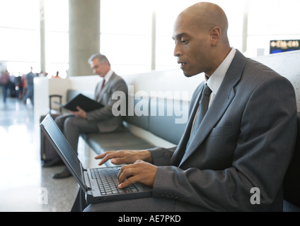 Geschäftsmann mit Laptop in Flughafen-Lounge-Bereich Stockfoto