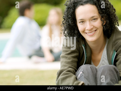 Junge Frau sitzt mit knien sich lächelnd Stockfoto