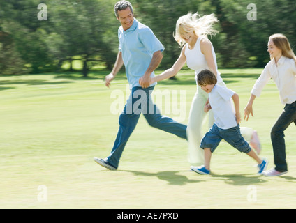 Familie Hand in Hand und läuft über den Rasen Stockfoto