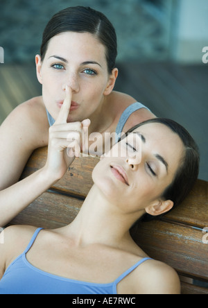 Junge Frau mit Finger auf die Lippen, während ihr Freund schläft, Porträt Stockfoto