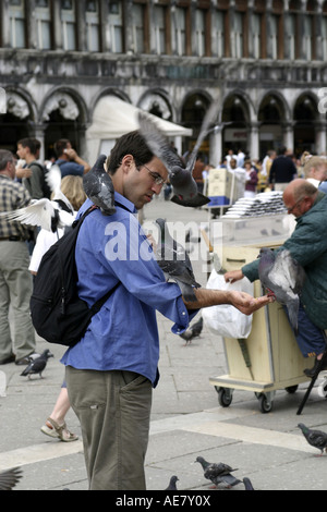 Mann füttern Tauben auf St. Markus Platz, Italien, Venedig Stockfoto