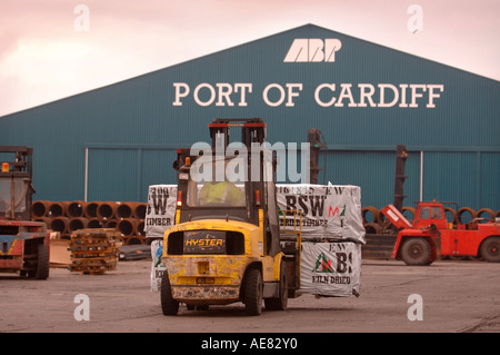 EIN GABELSTAPLER BEWEGEN PALETTEN AUS HOLZ AUF DAS DOCKSIDE EINEN HAFEN IN CARDIFF SOUTH WALES UK Stockfoto