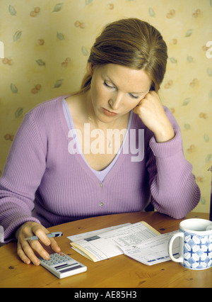 Junge Frau, die Überprüfung von Rechnungen, die Verwendung eines Taschenrechners Stockfoto