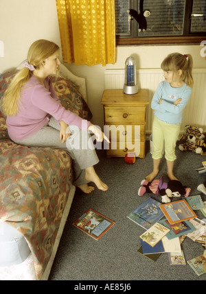 Mutter erzählte Sie ihr Kind in ihrem chaotisch Schlafzimmer Stockfoto