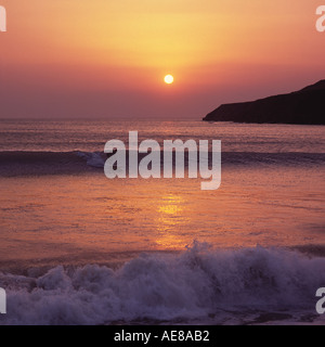 Surfer in unten Hockerlage zieht auf Welle Silhouette gegen Sonnenuntergang am Saunton Sands Beach North Devon England Stockfoto