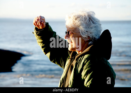 pensionierte Frau mit musste Abschirmung ihr Gesicht und die Augen vor der Sonne an der Küste Stockfoto