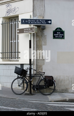 Fahrrad mit Korb angekettet um auf Straße Ecke der Rue Saint-Louis de Lile auf Ile St. Louis Paris Frankreich buchen Stockfoto