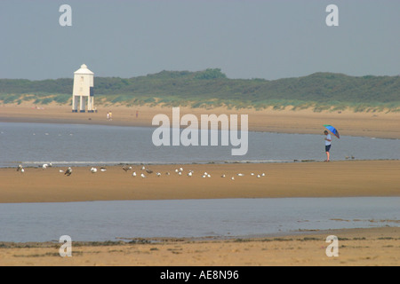 Burnham auf Meer Strand und Leuchtturm Mann mit Sonnenschirm im Vordergrund Stockfoto