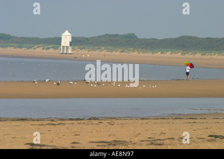 Burnham auf Meer Strand und Leuchtturm Mann mit Sonnenschirm im Vordergrund Stockfoto