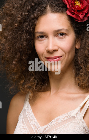 Close up Portrait of Hispanic Frau lächelnd mit Blume im Haar Stockfoto