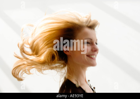 Porträt einer jungen Frau Smilng, blondes Haar, Bewegungsunschärfe Stockfoto