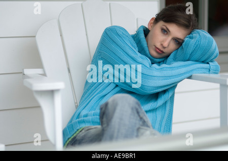 Junge Frau auf einem Stuhl sitzend schaut in die Kamera, im freien Stockfoto