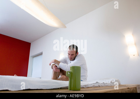 IPod-Player Mann sitzt auf einem Bett Stockfoto