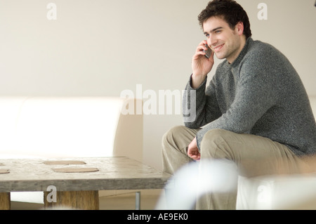 Mann sitzt auf einem Sofa mit einem Mobiltelefon Stockfoto