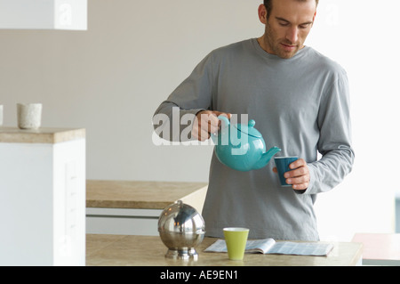 Mann in der Küche stand, Tee in ein Glas gießen Stockfoto