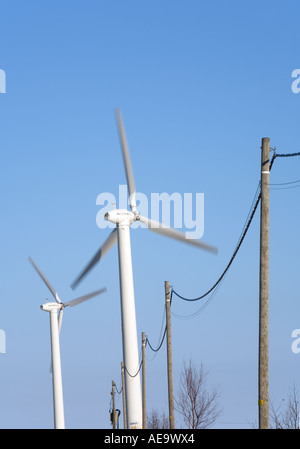 Zwei Windkraftanlagen und eine Stromleitung gegen klaren blauen Himmel, Finnland Stockfoto