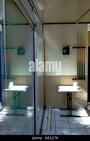 ein einsamer Tisch mit Rack mit Pool Queues an Wand reflektieren in einem Zeitfenster von einer Bar in Frankreich Stockfoto