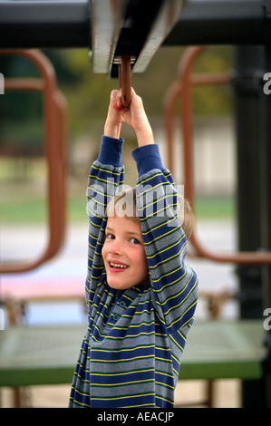 Ein sieben Jahre alter Junge spielt auf den Spielplatz-bars Stockfoto