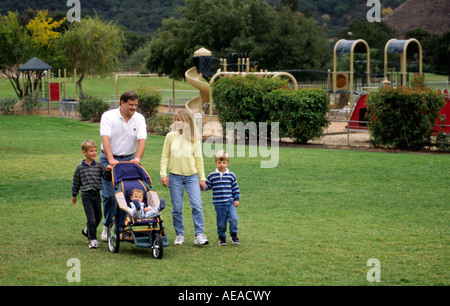 Mama Papa gehen für einen Spaziergang mit ihren drei Kindern Herr Stockfoto
