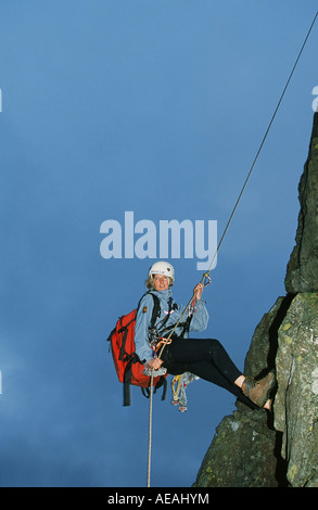 Eine weibliche Mountain Rescue Team Meber Abseilen ein Fels im Lake District, UK Stockfoto