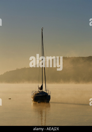 Ein Segelboot am Lake Windermere an einem nebligen Wintern Morgen, Lake District, Großbritannien Stockfoto