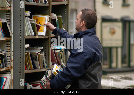 Ein Mann Auswahl Bücher in Open-Air-Buchhandlung in Hay on Wye, die zweite Hand Buch Hauptstadt der Welt, Powys, Wales UK kaufen Stockfoto