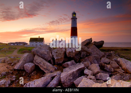 Portland Bill Leuchtturm und Halter Häuschen kurz vor der Morgendämmerung mit einem Durcheinander Haufen von Portland-Stein Felsbrocken im Vordergrund Stockfoto