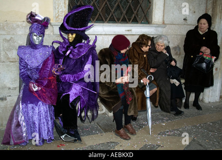 Kostümierte Karnevals, die Besucher neben älteren Damen beim Karneval in Venedig, Veneto, Italien sitzen Stockfoto