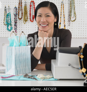 Mittleren Alters asiatischen weiblichen Boutique-Besitzer lächelnd hinter Theke Stockfoto