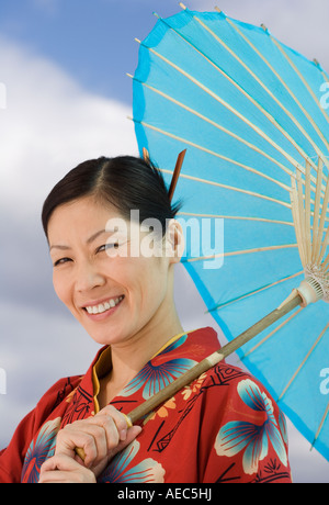 Asiatische Frau mittleren Alters in traditioneller Tracht mit Sonnenschirm Stockfoto