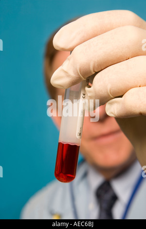 Forscher mit Handschuhen eine rote Probe in Testtube hält. Stockfoto